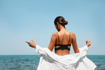 Fototapeta na wymiar Young woman in stylish bikini near sea on sunny day, back view
