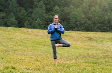 Obraz premium Mature woman in a forest practicing yoga, copy space. Mental health.