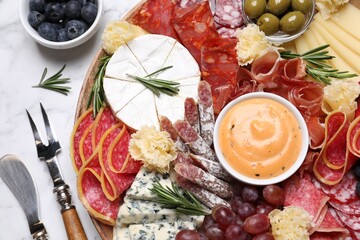 Wooden plate with different delicious snacks on white marble table, flat lay