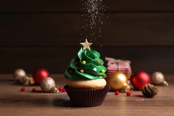 Sprinkling powdered sugar on Christmas tree shaped cupcake