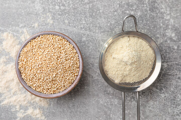 Quinoa flour in sieve and bowl with seeds on light grey table, flat lay