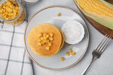 Tasty corn pancakes with sauce served on light grey table, flat lay