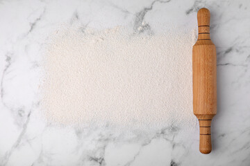 Frame made of flour and rolling pin on white marble table, top view. Space for text