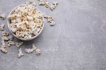 Bowl of tasty popcorn on grey table, flat lay. Space for text