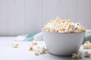 Bowl of tasty popcorn on white table, space for text
