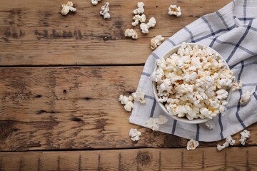 Bowl of tasty popcorn on wooden table, flat lay. Space for text