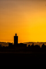 Silhouette of a typical Arab village with a mosque minaret at sunset. Ksar Tanamouste, Sahara, Morocco.