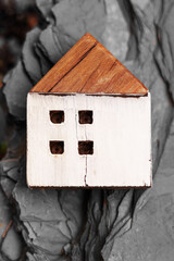 Wooden cracked homemade house model on natural black stone