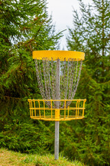 Golf disc basket in a natural park with coniferous evergreen trees