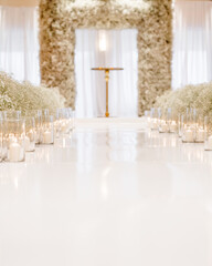 Wedding ceremony decorations with the white road between candles and large arch with fresh flowers on background of window