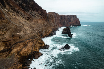 Rocky coastal peninsula Ponta de Sao Lourenco in Madeira island cliffside against dramatic ocean waves under cloudy skies
