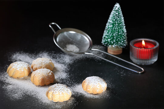 Small biscuits, red lit candle, green christmas tree, colander, dark background