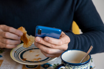 person looks at the smartphone while having breakfast
