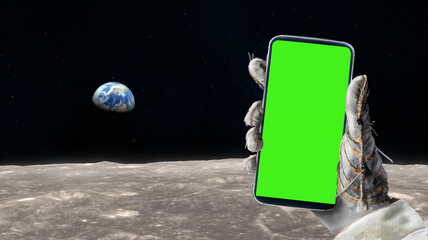 Astronaut gloves hand holds a smartphone with green screen chroma key on surface of the moon making...