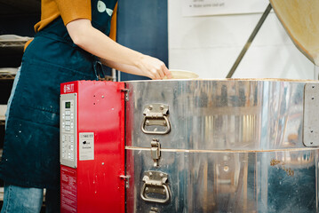 Potter unloading ceramic kiln in studio. Woman potter hands.