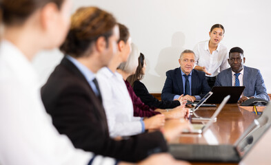 Multiracial group of two mature male senior executives in formal suits holding business team meeting in conference hall