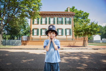 Adorable elementary school aged boy wearing an Abraham Lincoln top hat visiting the Lincoln Home in Springfield, Illinois
