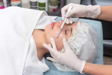 skin treatment with the dermaplaning technique performed with a scalpel by a beautician in a center...