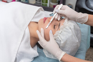 skin treatment with the dermaplaning technique performed with a scalpel by a beautician in a center...