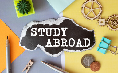 The text Study Abroad appearing behind torn brown paper