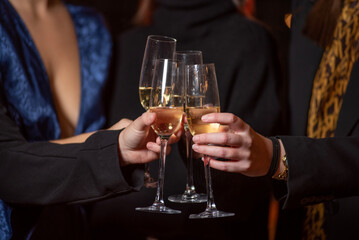 detail of hands toasting with glasses of champagne, hands of girls in elegant dresses