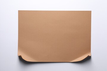 Empty kraft paper sheet with curved borders isolated on white, top view