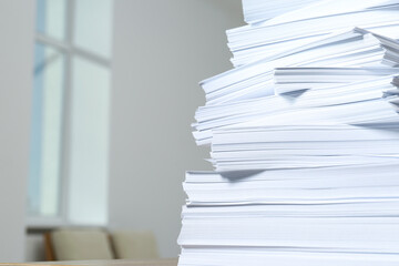 Stack of paper sheets against blurred background, closeup. Space for text