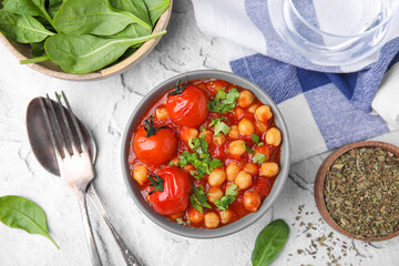 Delicious chickpea curry and seasoning in bowl on white textured background, flat lay