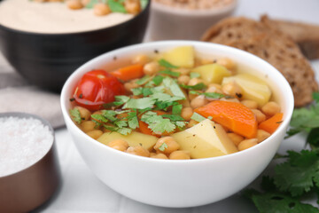 Tasty chickpea soup in bowls on white table, closeup
