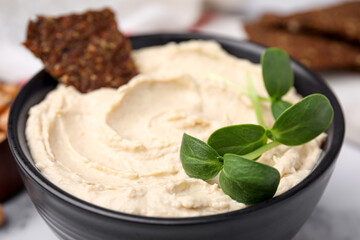 Bowl of delicious hummus with crispbread, closeup