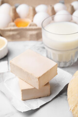 Fototapeta na wymiar Blocks of compressed yeast and ingredients on white marble table, closeup