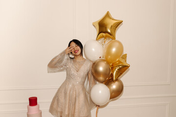 Wonderful young asian girl closing her eyes with hands smiling on white background with balloons....