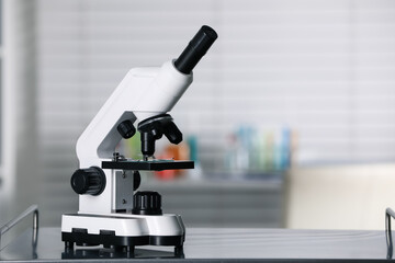 Modern medical microscope on metal table in laboratory, space for text