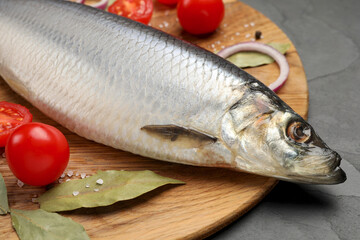 Tray with salted herring, onion, bay leaves and cherry tomatoes on black table, closeup