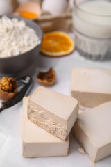 Blocks of compressed yeast and ingredients for dough on white table