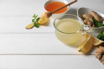Delicious ginger tea and ingredients on white wooden table, space for text