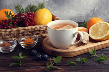 Cup of delicious immunity boosting tea and ingredients on wooden table