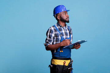 Portrait of construction contractor checking the task list on clipboard, looking carefully to make...