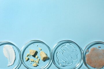 Many petri dishes with samples on light blue background, flat lay. Space for text