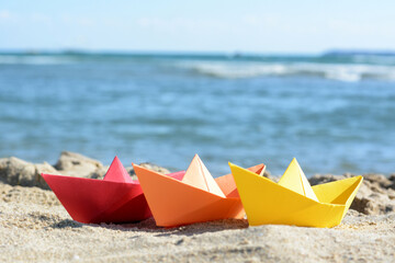 Three paper boats near sea on sunny day
