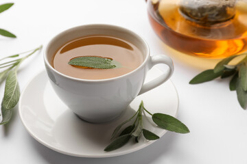 Aromatic herbal tea with sage on white table