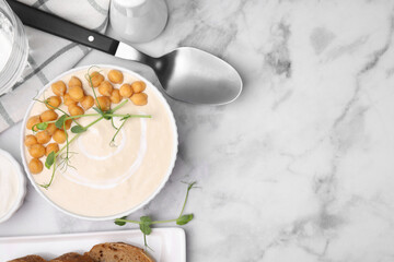Flat lay composition of tasty chickpea soup in bowl, sauce and bread served on white marble table. Space for text