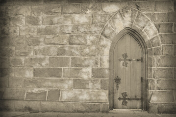 Black and white off center church door in a hefty stone wall. Old-fashioned look and vintage feel, with copy space, no people, and digital hand-drawn effect. Romantic antique photo look.