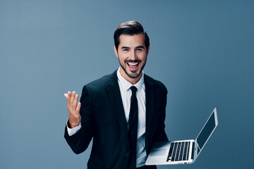 Man business looks into laptop and works online smiling fist up online in business suit video call business negotiations win on gray background copy place