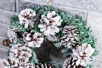 Christmas wreath made of fir branches and natural cones. Against the background of a gray brick wall. New Year and winter holidays. Christmas decor