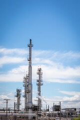 Silver Colored Smoke Stacks at an Oil Refinery Against a Blue Sky With Clouds