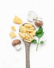 Raw pasta with mushrooms and parmesan in a wooden spoon on a white background
