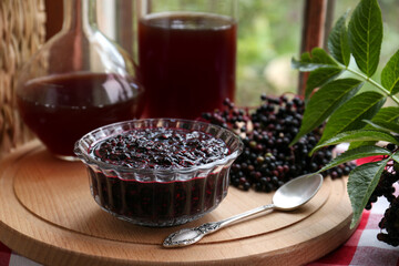 Elderberry jam and drink with Sambucus berries on table near window
