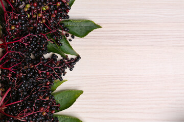 Tasty elderberries (Sambucus) on wooden table, top view. Space for text