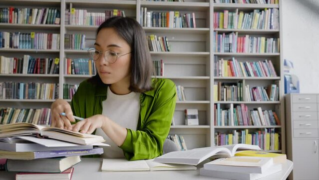 Young Asian teacher writes theses using books in library